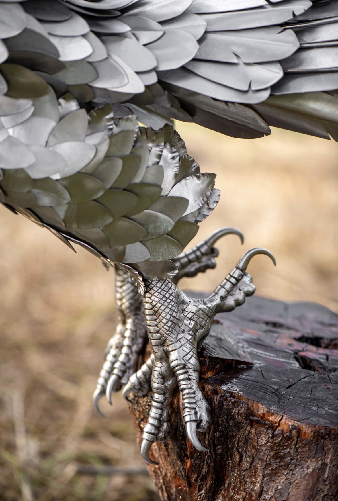 Detail of the sculpted stainless steel talons gripping a wooden stump